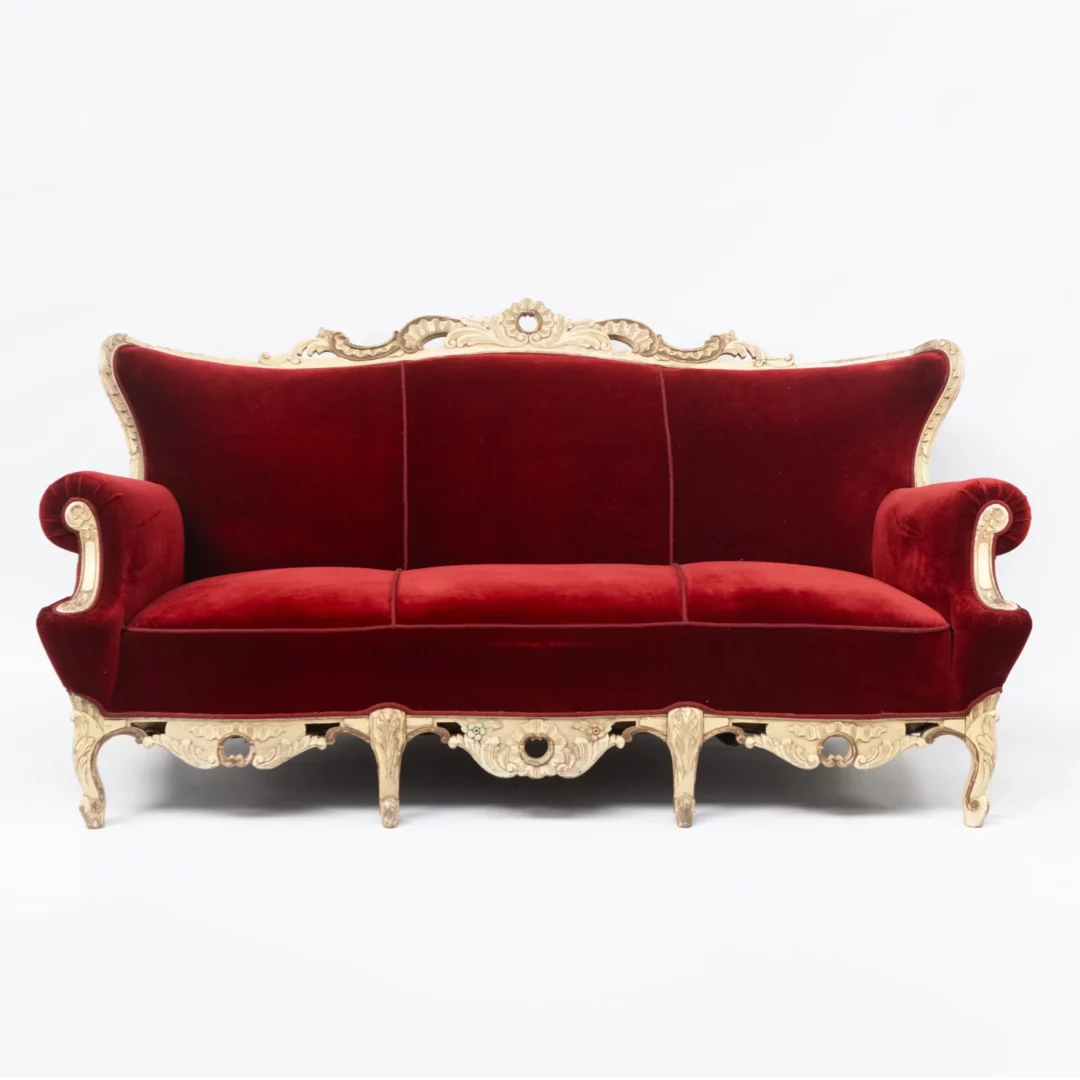 Sofa Barokowa Królewska. Elegancka sofa w stylu barokowym w kolorze głębokiej czerwieni z rzeźbioną, drewnianą ramą, idealna do wynajmu na różne eventy we Wrocławiu. Charakterystyczne pikowanie oraz zaokrąglone podłokietniki dodają klasy i luksusu. Klasyczny barokowy design sprawia, że sofa doskonale nadaje się jako element scenografii oraz do eleganckich stref chillout na ślub, wesele lub dowolne wydarzenie. Miękkie, aksamitne wykończenie w połączeniu ze bogatymi rzeźbieniami tworzy wyjątkowy mebel. Dostępna w wypożyczalni dekoracji RENT4EVENTS, ta sofa łączy w sobie elegancję i wygodę, tworząc perfekcyjne miejsce do siedzenia na każdym evencie - rent4events.pl wypożycz wrażenia, rent4wedding.pl zachowaj wspomnienia.