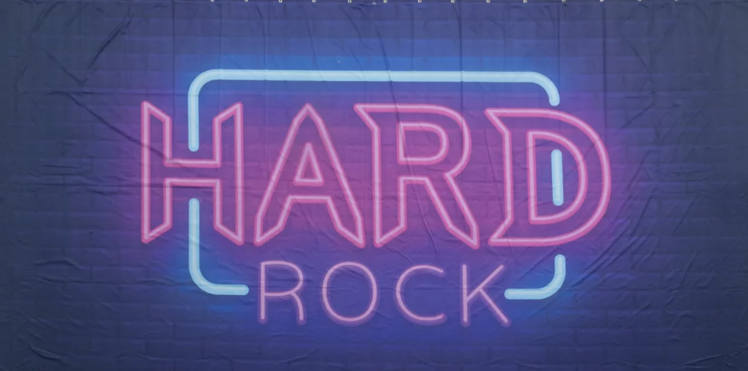 Horyzont Muzyka Hard Rock. Fotograficzne tło przedstawiające neonowy napis "HARD ROCK" w jaskrawo różowym i niebieskim kolorze na ciemnym tle. Tło to doskonale oddaje klimat nocnych imprez i koncertów rockowych, nadając się idealnie na eventy i wesela w klimacie muzyki rockowej. Neonowy styl oraz intensywne kolory w połączeniu z ciemnym tłem tworzą dynamiczny i energetyczny efekt. To tło sprawdzi się na imprezach organizowanych przez wypożyczalnię dekoracji Rent4Events we Wrocławiu - rent4events.pl wypożycz wrażenia, rent4wedding.pl zachowaj wspomnienia.