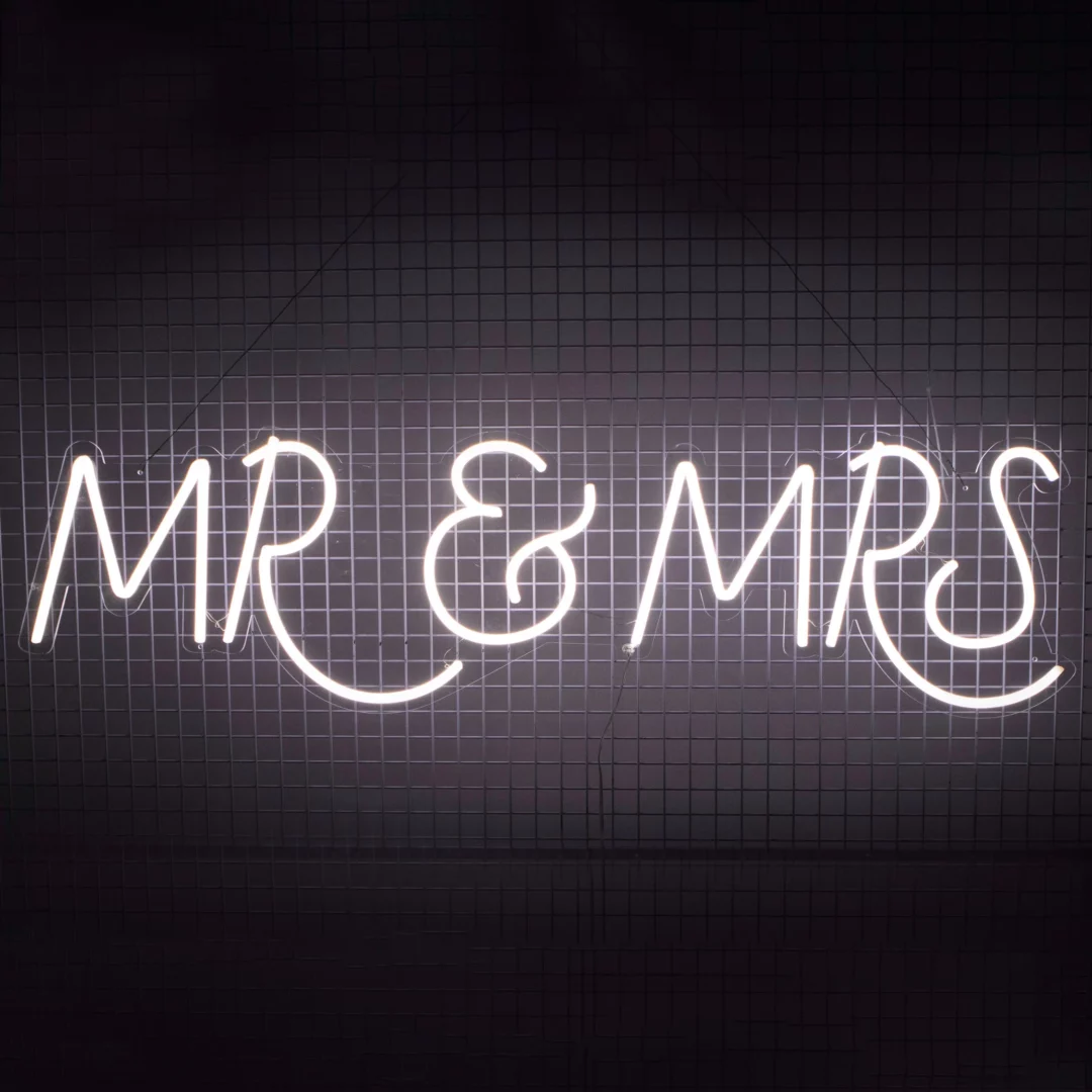 Neon MR & MRS. Ledonowy napis "MR & MRS" o zimnej, białej barwie światła, zapalony, w ciemnym otoczeniu, przyczepiony na kratownicy. Idealna dekoracja tworząca nowoczesny klimat. Doskonale sprawdzi się jako element scenografii na ślubach, weselach czy rocznicach ślubów. Oferujemy wynajem takich dekoracji na rent4events.pl oraz rent4weddings.pl - rent4events.pl wypożycz wrażenia, rent4wedding.pl zachowaj wspomnienia.