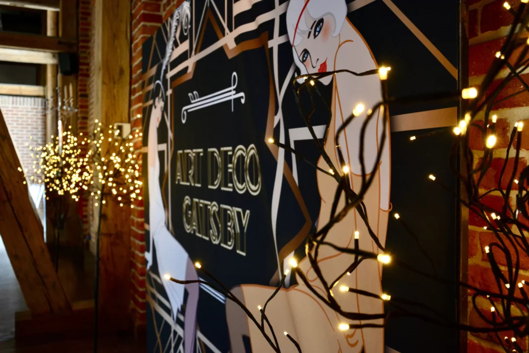 Horyzont Gatsby Art Deco. Wypożyczalnia dekoracji rent4events.pl oferuje luksusowe rozwiązania na eventy, wesela i przyjęcia tematyczne. Dekoracja w stylu „Art Deco Gatsby” zawiera elegancki napis oraz stylowe grafiki kobiet z lat 20. XX wieku, które w połączeniu z subtelnym oświetleniem tworzą wytworną atmosferę. Ceglana ściana w tle dodaje rustykalnego, industrialnego charakteru, co doskonale komponuje się z eleganckim stylem Art Deco. Dekoracja idealna na prestiżowe przyjęcia, dostępna we Wrocławiu na rent4events.pl oraz na śluby na rent4weddings.pl. rent4events.pl – wypożycz wrażenia, rent4wedding.pl – zachowaj wspomnienia.