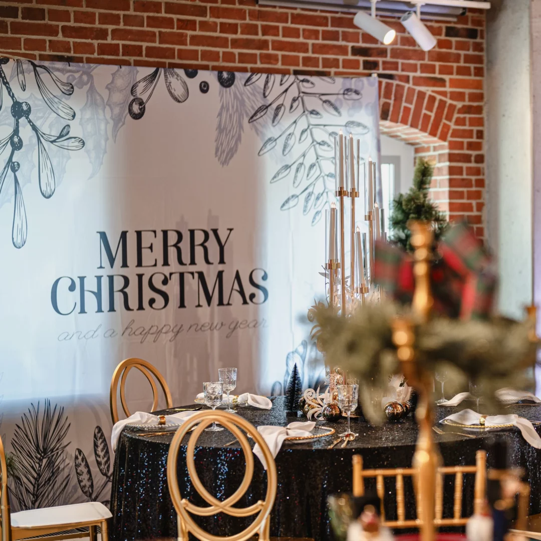 Elegancki baner „Merry Christmas” w tle świątecznej aranżacji stołu, z czarnym, błyszczącym obrusem cekinowym, złotymi krzesłami oraz świątecznymi dekoracjami. Minimalistyczne i nowoczesne dekoracje, idealne na świąteczne wesela, eventy lub przyjęcia, dostępne w wypożyczalni rent4events.pl we Wrocławiu. Sprawdź również ofertę na śluby na rent4weddings.pl. rent4events.pl – wypożycz wrażenia, rent4wedding.pl – zachowaj wspomnienia. Fot. @karolinakiec_fotografia.